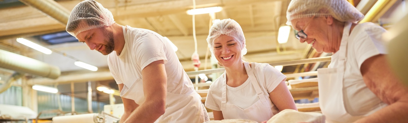 Bäcker stehen in der Backstube und backen Brot