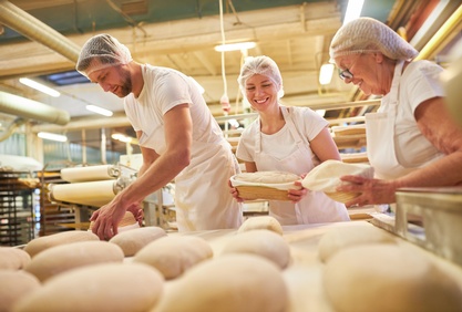 Bäcker stehen in der Backstube und backen Brot