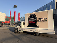 Ein Werbe-LKW mit einem Plakat gegen eine „Todessteuer“ steht vor der Messe Wien, während Menschen im Hintergrund zum SPÖ-Parteitag gehen