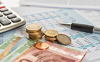 Taschenrechner, Euro-Münzen, Euro-Scheine und Kugelschreiber